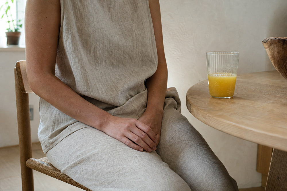 A woman's hands resting on a kitchen table in morning light beside a glass of the prepared Daily Calm Focus drink
