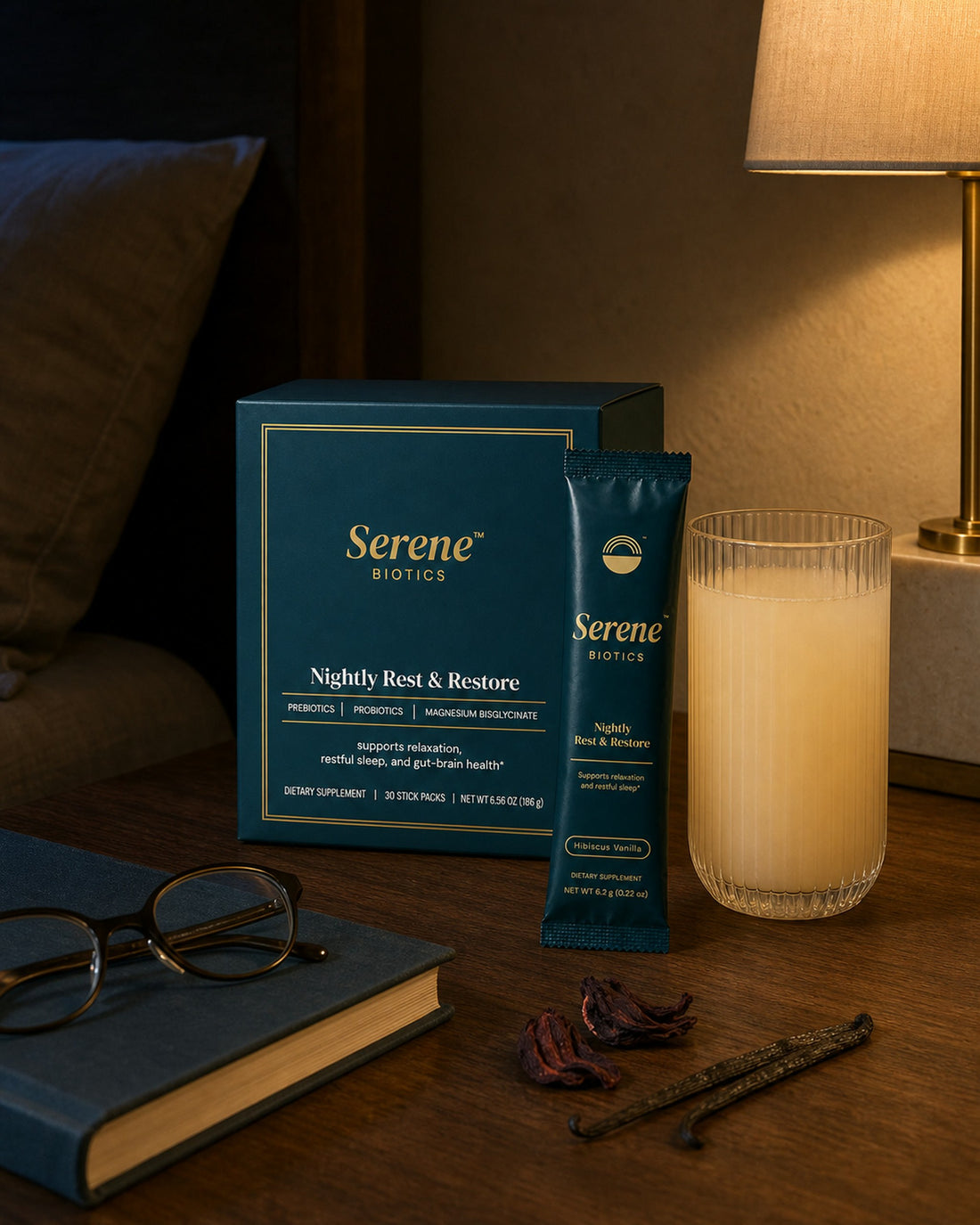 Nightly Rest and Restore on a lamplit nightstand with the pale glowing drink, a book, and reading glasses