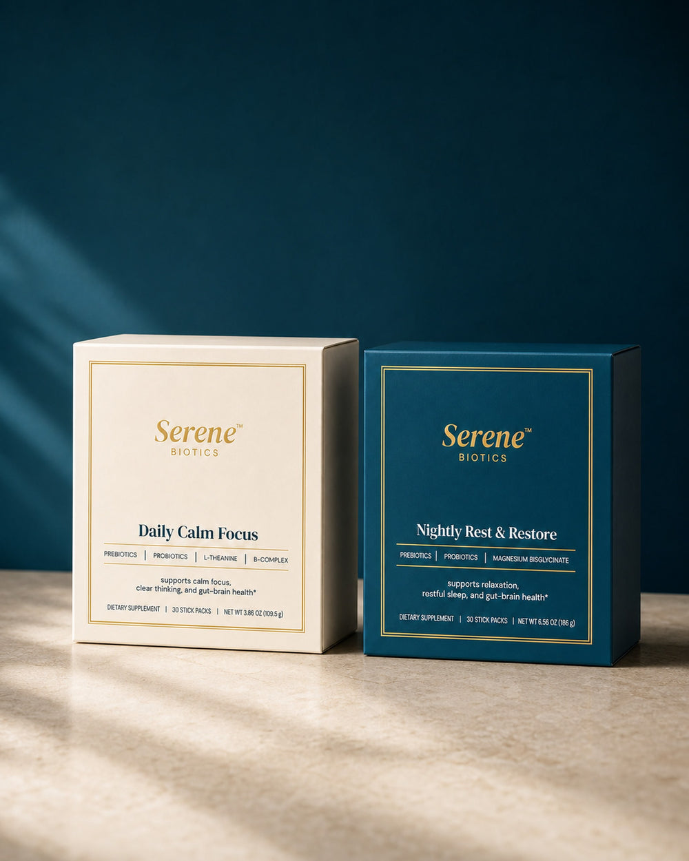 The cream Daily Calm Focus carton and the teal Nightly Rest & Restore carton standing side by side on warm stone against a deep teal wall