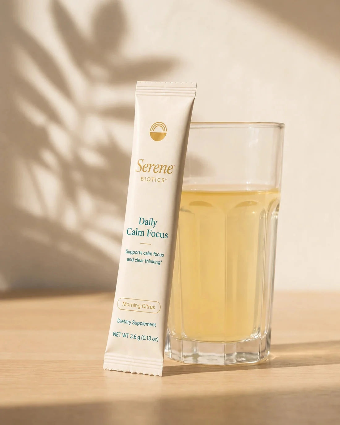 Serene Biotics Daily Calm Focus stick pack beside a prepared Peach Mango drink